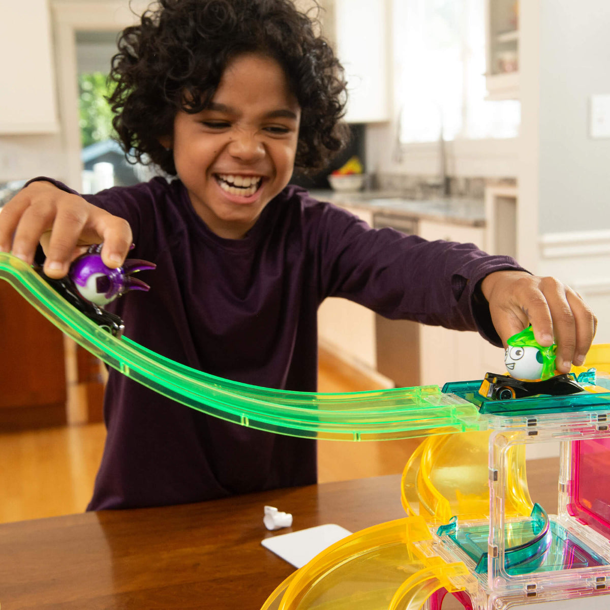 Boy playing with Erggs characters in their cars on top of a Squaregles build