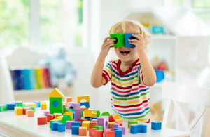 Boy playing with wooden blocks and holding two up to his eyes